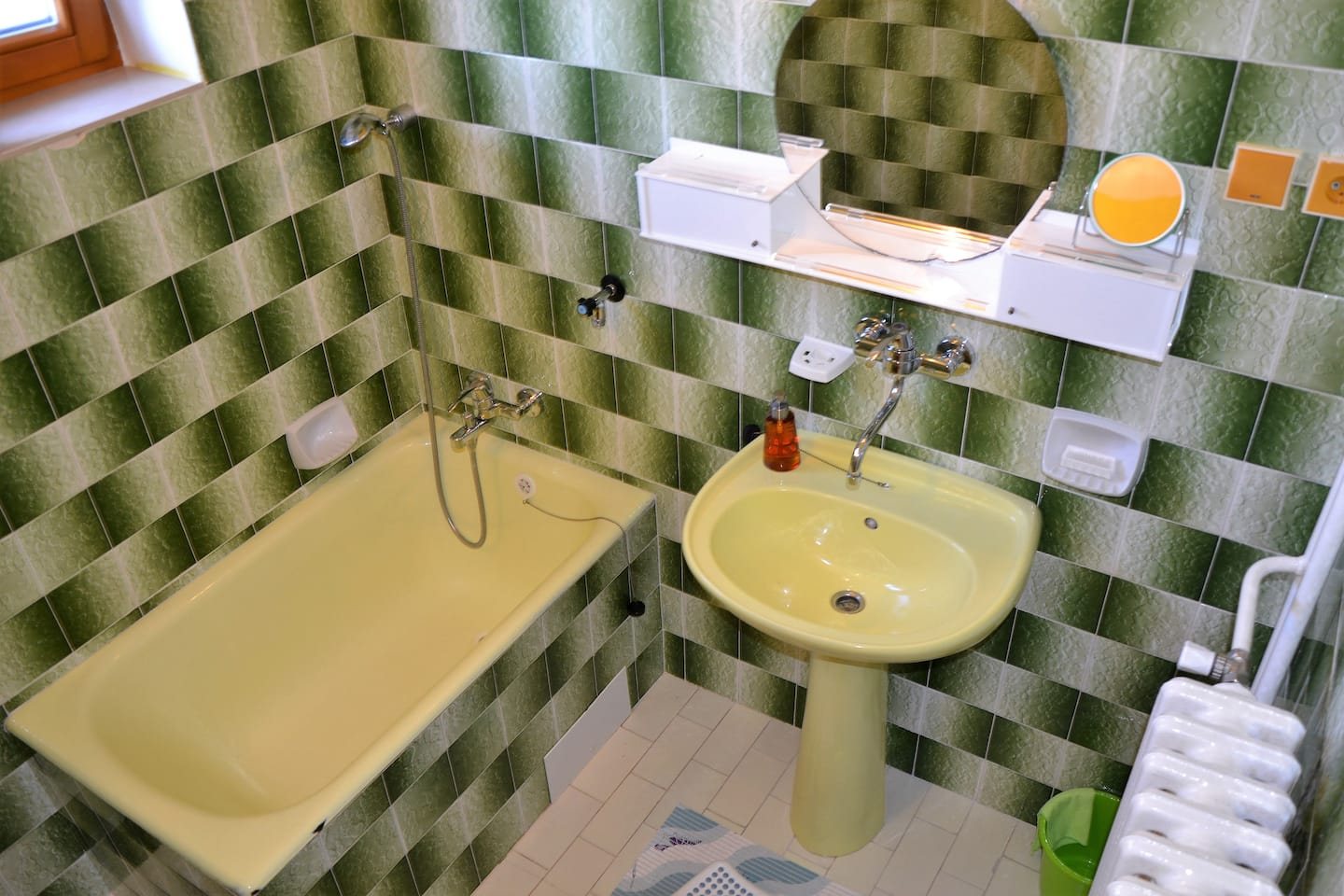 Koupelna se zeleným šachovnicovým obkladem a žlutou vanou